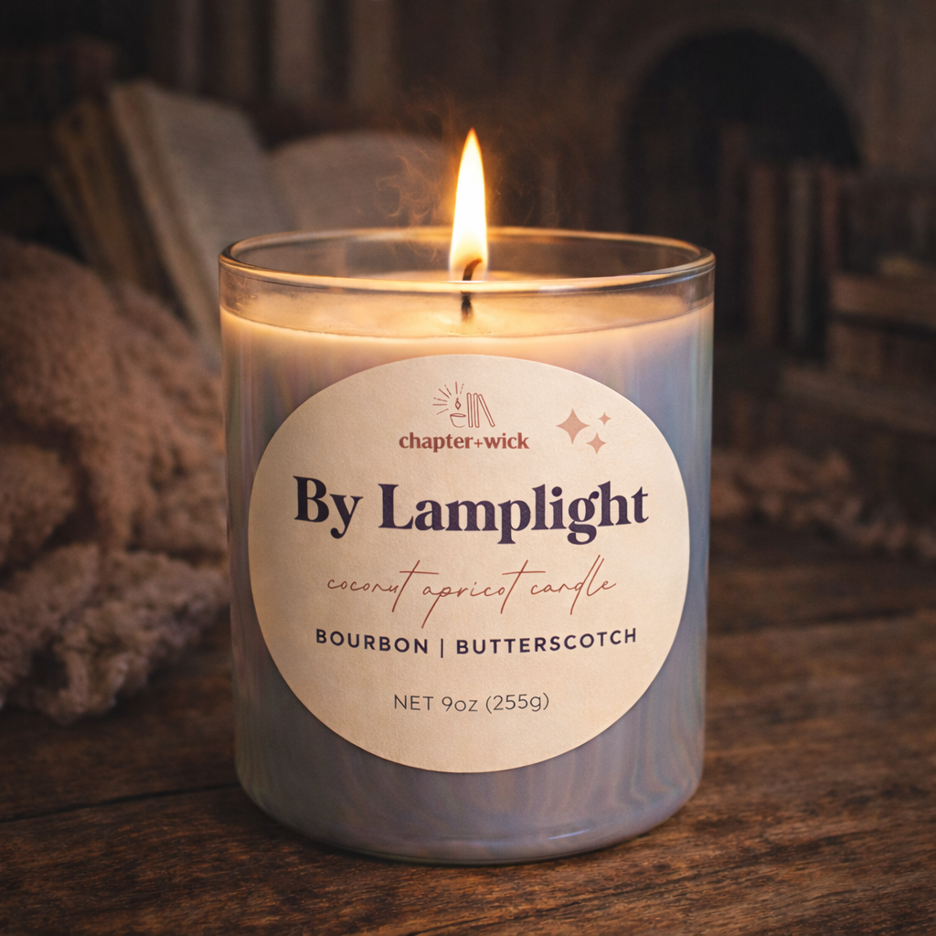 Candle labeled 'By Lamplight' on a wooden surface with a warm glow.