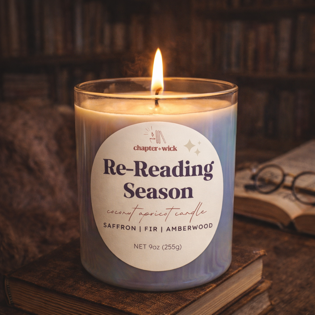 Candle labeled 'Re-Reading Season' on a wooden surface with books and glasses in the background